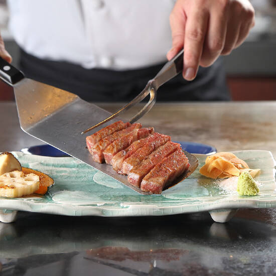 鉄板で焼いたお肉をお皿に盛り付けるシェフの手元